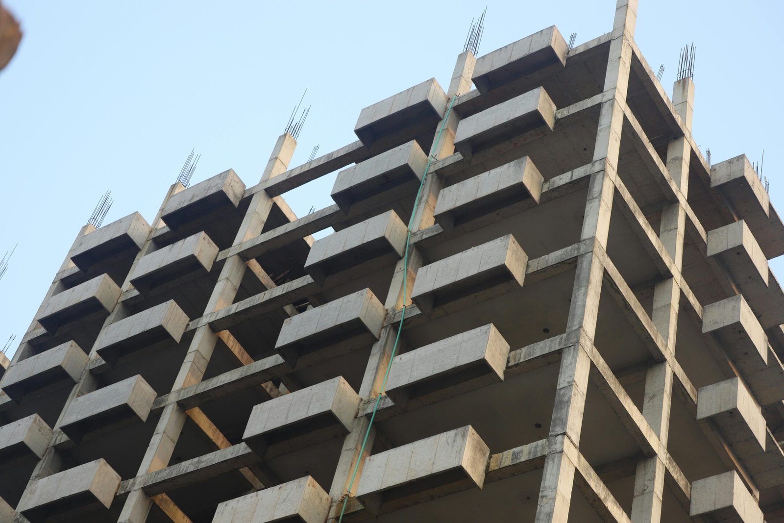 A concrete building skeleton under construction with visible beams and sky backdrop.